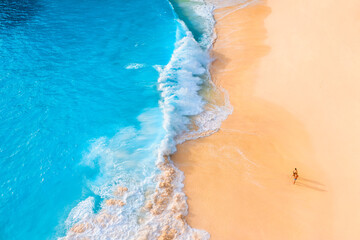 Wall Mural - An aerial view of the people on the beach. Coast as a background from top view.  Waves and beach. Seascape. Azure water background from drone. Vacation time.
