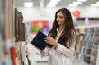 © Mihail - woman in the book store holding a book and reading it
