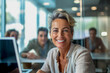 © Six Hen Media - A confident and successful mature businesswoman sitting at her desk in a professional office environment.