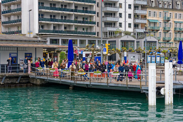 Wall Mural - People waiting at pier of Swiss City of Brunnen for paddle steamer passengers ship on a cloudy spring day. Photo taken May 18th, 2023, Brunnen, Canton Schwyz, Switzerland.
