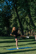 © Guys Who Shoot - young sportswoman girl doing physical exercises on a sports mat training with rubber bands on her legs outside in the park healthy lifestyle concept