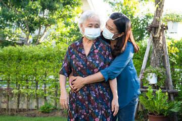 Wall Mural - Caregiver help Asian elderly woman patient wearing face mask walk in park, healthy strong medical concept.