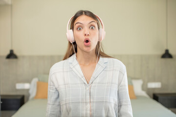 Wall Mural - young pretty woman feeling extremely shocked and surprised. headphones concept