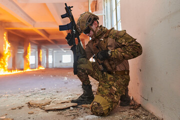 Soldier in action near window changing magazine and take cover