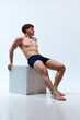 Full-length image of young man with muscular body posing shirtless in underwear against white studio background. Concept of man's beauty, sportive and healthy lifestyle, athletic body