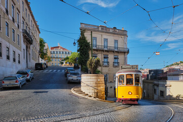 Famous vintage yellow tram 28 in the narrow streets of Alfama district in Lisbon, Portugal - symbol of Lisbon, famous popular travel destination and tourist attraction