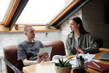 Leinwandbilder - Young confident businesswoman explaining something to male colleague using tablet and looking at female employee during discussion