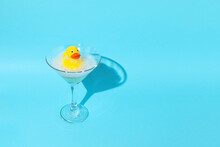 Yellow Duck In A Martini Glass On A Blue Background. Creative Concept.