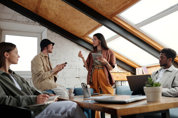 Aufkleber - Young confident businesswoman with tablet explaining her idea to male colleague while standing in front of two intercultural coworkers