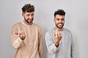 Wall Mural - Young homosexual couple standing over white background beckoning come here gesture with hand inviting welcoming happy and smiling