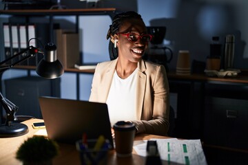 Sticker - Beautiful black woman working at the office at night looking away to side with smile on face, natural expression. laughing confident.