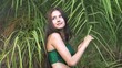 © Maksim - A young woman in a green swimsuit standing in front of exotic plants