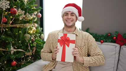 Sticker - Young hispanic man smiling confident holding christmas gift at home