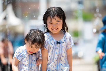 Poster - 広場の噴水で水遊びしている女の子