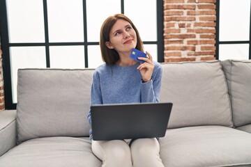 Sticker - Young blonde woman shopping with laptop and credit card thinking at home