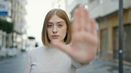 Poster - Young blonde woman doing stop gesture with hand at street