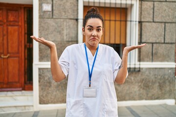 Sticker - Young hispanic woman wearing doctor id card shouting and screaming loud to side with hand on mouth. communication concept.