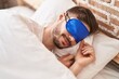 Young caucasian man wearing sleep mask lying on bed sleeping at bedroom