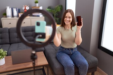 Sticker - Beautiful brunette woman recording vlog tutorial with smartphone at home smiling happy pointing with hand and finger to the side