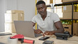 © Krakenimages.com - African american man ecommerce business worker using smartphone and laptop at office