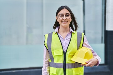 Wall Mural - Young hispanic woman architect smiling confident holding hardhat at street