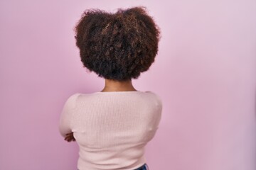 Canvas Print - Young african american woman standing over pink background standing backwards looking away with crossed arms