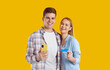 Happy couple send money transfer, shop online or receive bonus. Joyful Caucasian boyfriend and girlfriend in casual shirts smile, look at camera and show mobile phone and credit card. Studio portrait