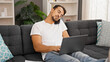 © Krakenimages.com - Young hispanic man talking on smartphone using laptop at home