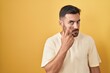 © Krakenimages.com - Handsome hispanic man standing over yellow background pointing to the eye watching you gesture, suspicious expression
