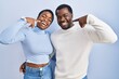 © Krakenimages.com - Young african american couple standing over blue background smiling cheerful showing and pointing with fingers teeth and mouth. dental health concept.