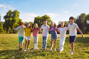 Children playing together in nature. Group of happy best friends having summer season break, doing fun activities, enjoying life, having good time, playing outdoor games under blue sky in green park