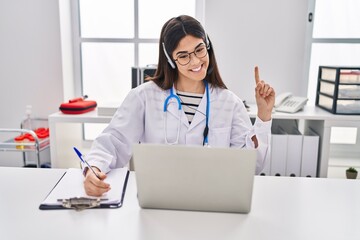 Poster - Young brunette woman working on online appointment smiling with an idea or question pointing finger with happy face, number one