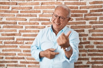 Sticker - Senior man with grey hair standing over bricks wall beckoning come here gesture with hand inviting welcoming happy and smiling