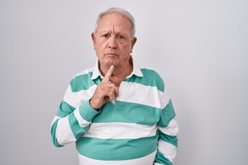 Sticker - Senior man with grey hair standing over white background thinking concentrated about doubt with finger on chin and looking up wondering