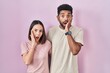 © Krakenimages.com - Young hispanic couple together over pink background afraid and shocked, surprise and amazed expression with hands on face
