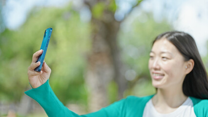 Poster - Young chinese woman smiling confident making selfie by the smartphone at park