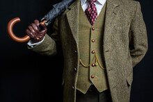 Portrait Of Vintage British Gentleman In Tweed Suit Holding Umbrella Over Shoulder.