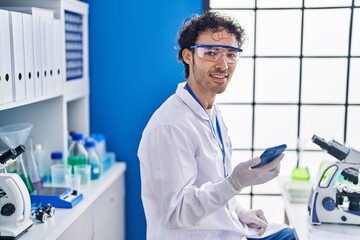 Sticker - Young hispanic man scientist using smartphone working at laboratory