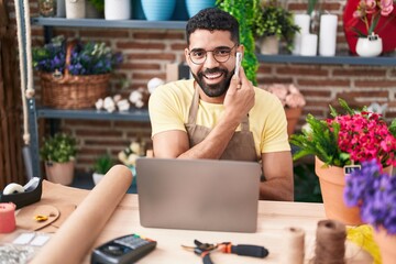 Sticker - Young arab man florist talking on smartphone using laptop at florist