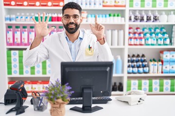 Sticker - Hispanic man with beard working at pharmacy drugstore showing and pointing up with fingers number seven while smiling confident and happy.