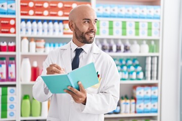 Sticker - Young bald man pharmacist smiling confident writing on document at pharmacy