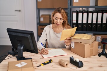 Canvas Print - Young woman ecommerce busines worker writing on notebook holding package at office