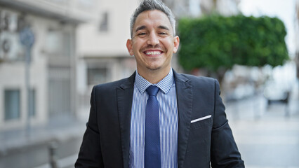 Young hispanic man business worker smiling confident standing at street