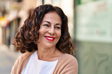 Wall Mural - Middle age hispanic woman smiling happy outdoors