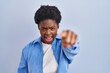 African american woman standing over blue background pointing displeased and frustrated to the camera, angry and furious with you