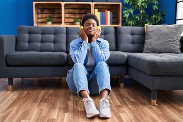 Poster - African american woman listening to music sitting on floor at home