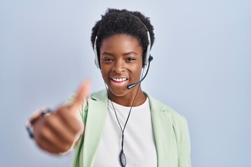 Poster - African american woman wearing call center agent headset approving doing positive gesture with hand, thumbs up smiling and happy for success. winner gesture.