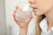 © Atlas - Young woman drinking water from a cup close-up