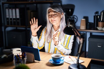 Poster - Middle age woman with grey hair working at the office at night showing and pointing up with fingers number eight while smiling confident and happy.