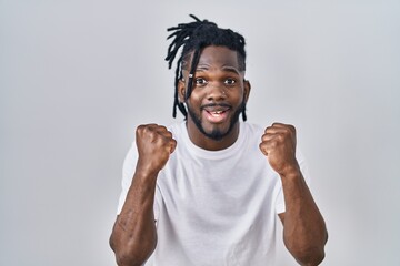 Poster - African man with dreadlocks wearing casual t shirt over white background celebrating surprised and amazed for success with arms raised and open eyes. winner concept.